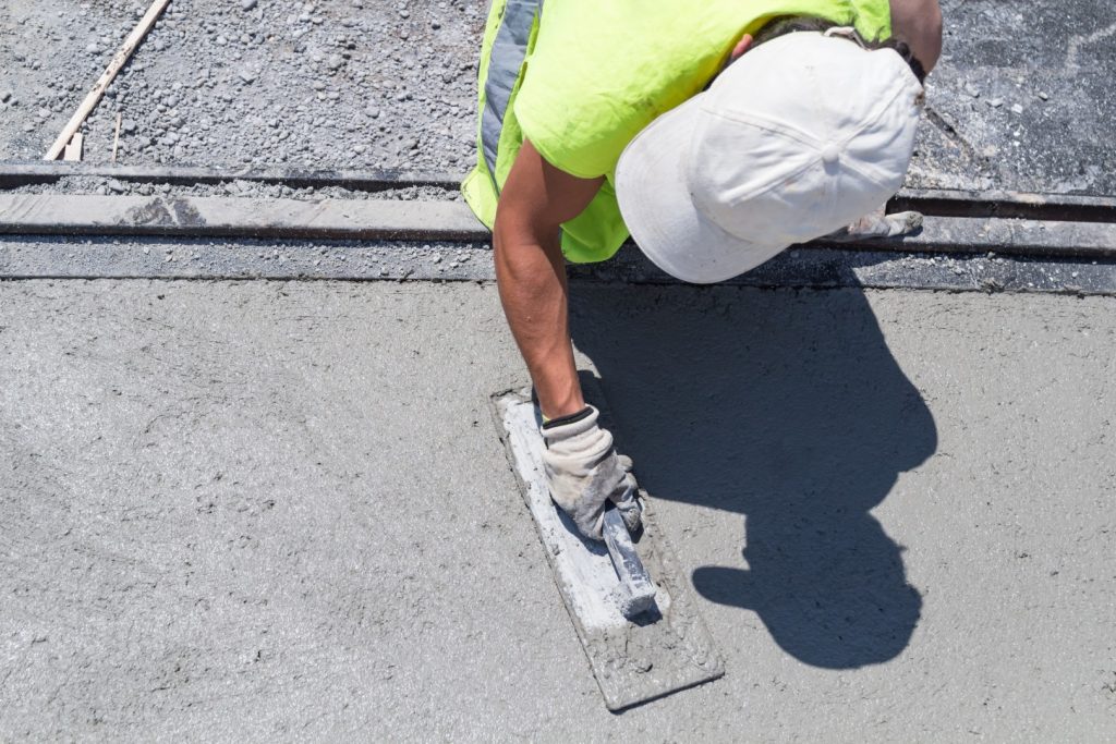 concrete worker smoothing out poured concrete